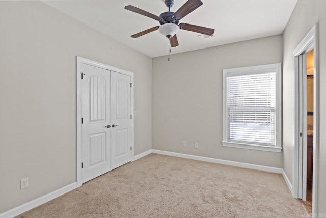 unfurnished bedroom with ceiling fan, light carpet, and a closet