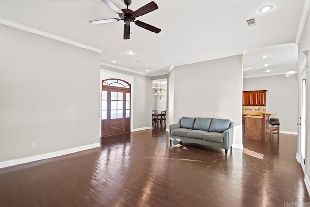 living room featuring ceiling fan with notable chandelier, dark wood-type flooring, and crown molding