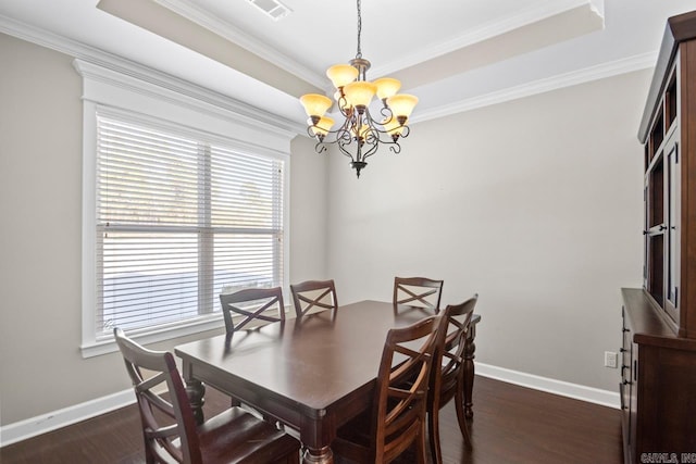 dining room with a chandelier, dark wood-type flooring, a raised ceiling, and crown molding