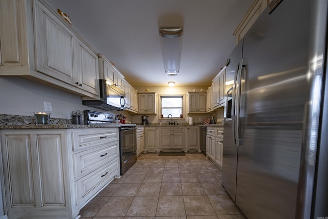 kitchen with stone counters, light tile patterned flooring, sink, and appliances with stainless steel finishes