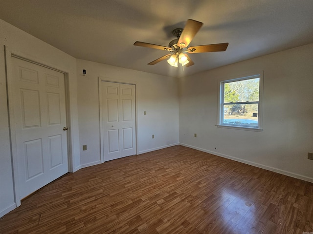 unfurnished bedroom with ceiling fan and dark hardwood / wood-style flooring