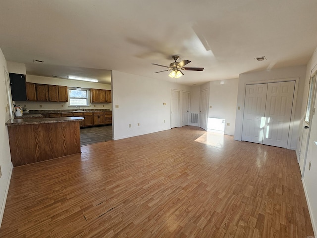 unfurnished living room featuring ceiling fan, dark wood-type flooring, and sink