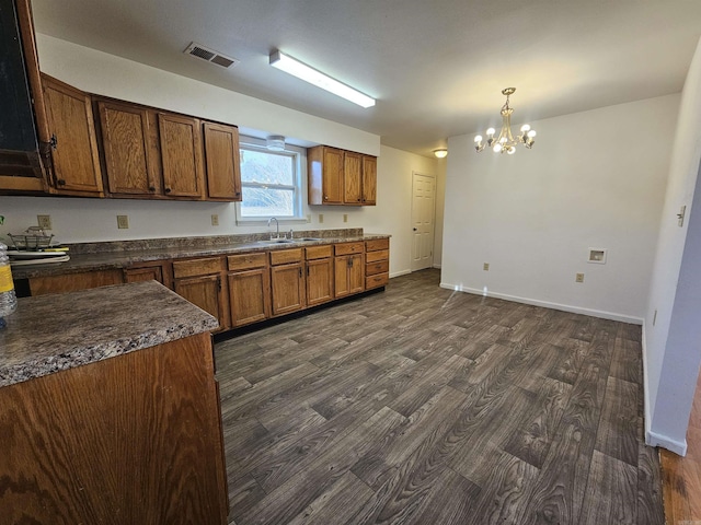 kitchen with a notable chandelier, decorative light fixtures, dark hardwood / wood-style flooring, and sink