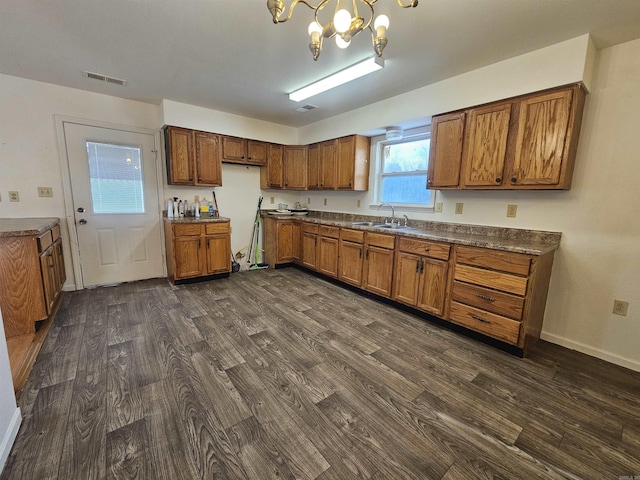 kitchen with dark wood-type flooring, an inviting chandelier, pendant lighting, and sink