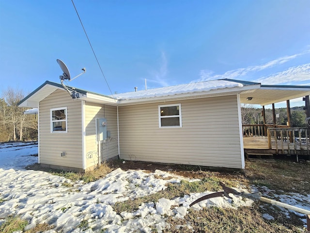 snow covered rear of property featuring a deck