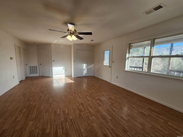 unfurnished living room with ceiling fan and dark wood-type flooring