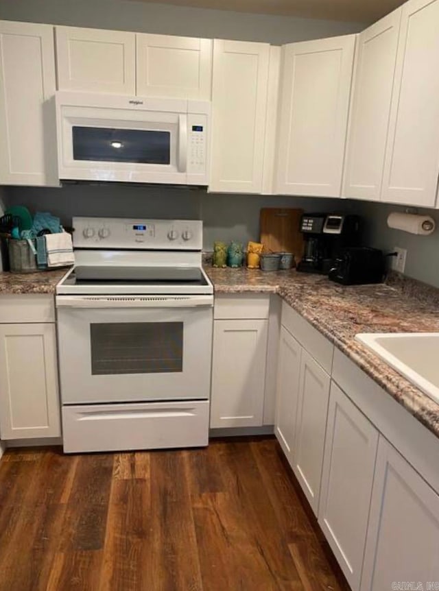 kitchen with sink, white appliances, light stone countertops, white cabinets, and dark hardwood / wood-style flooring