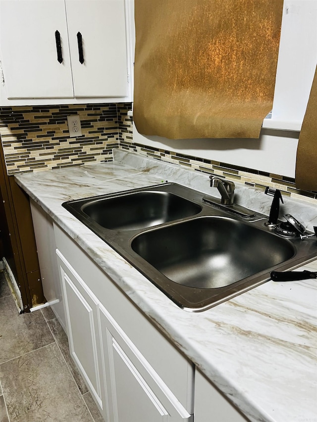 kitchen with decorative backsplash, white cabinetry, and sink