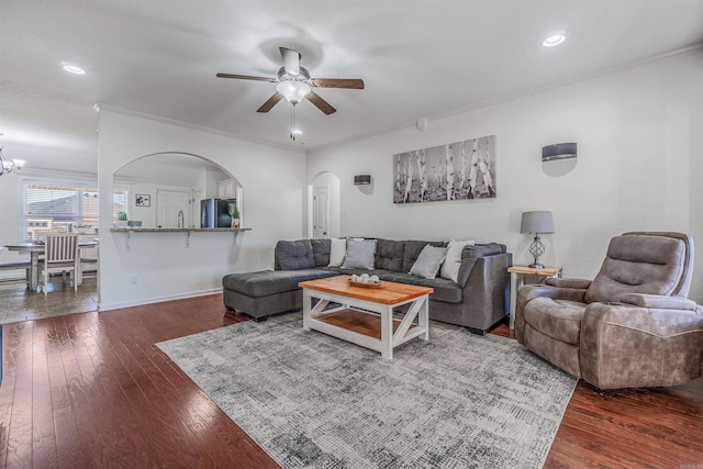 living room featuring dark hardwood / wood-style floors, crown molding, and ceiling fan with notable chandelier