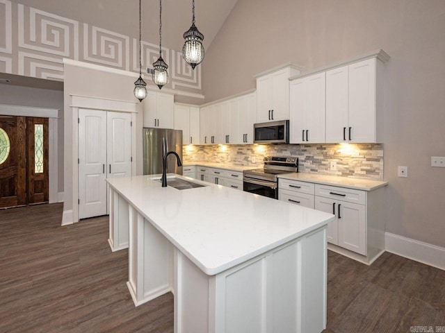 kitchen with appliances with stainless steel finishes, pendant lighting, a center island with sink, and sink