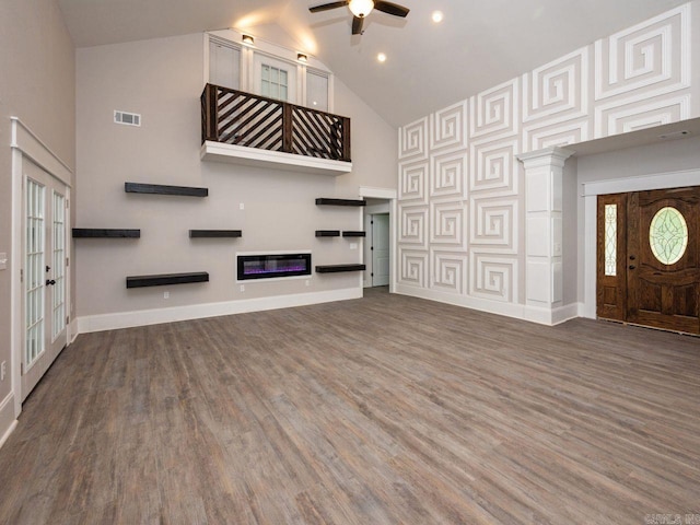 unfurnished living room featuring a high ceiling, ceiling fan, and dark hardwood / wood-style floors