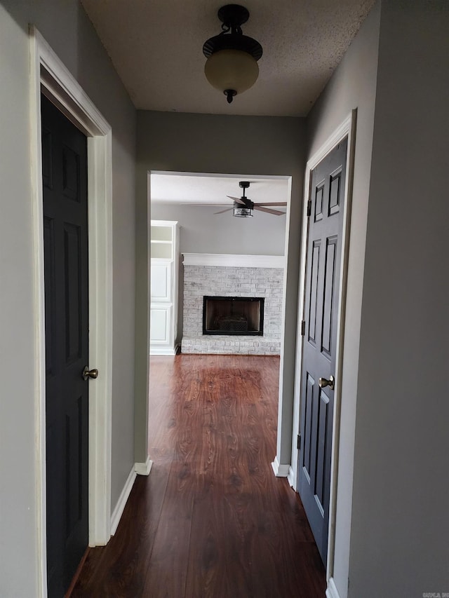 hall with a textured ceiling and dark hardwood / wood-style flooring