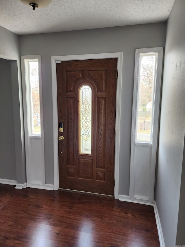 entrance foyer with dark hardwood / wood-style flooring and a textured ceiling