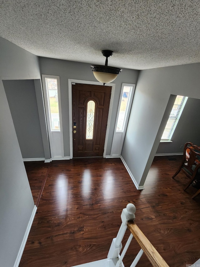 entryway with a textured ceiling and dark hardwood / wood-style flooring