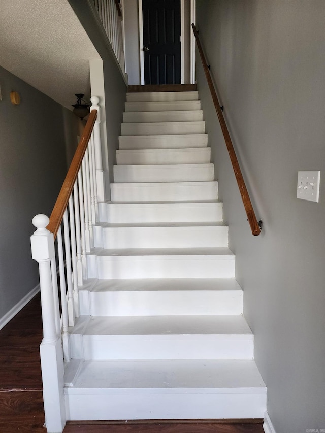 staircase featuring a textured ceiling and hardwood / wood-style floors