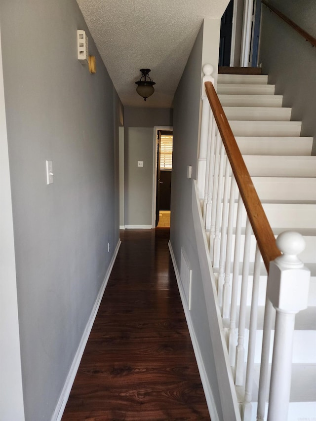 corridor with a textured ceiling and dark hardwood / wood-style floors