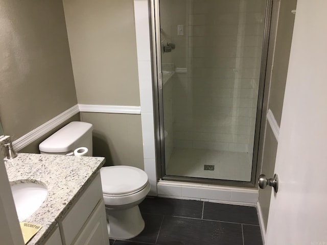 bathroom with toilet, a shower with door, vanity, and tile patterned floors