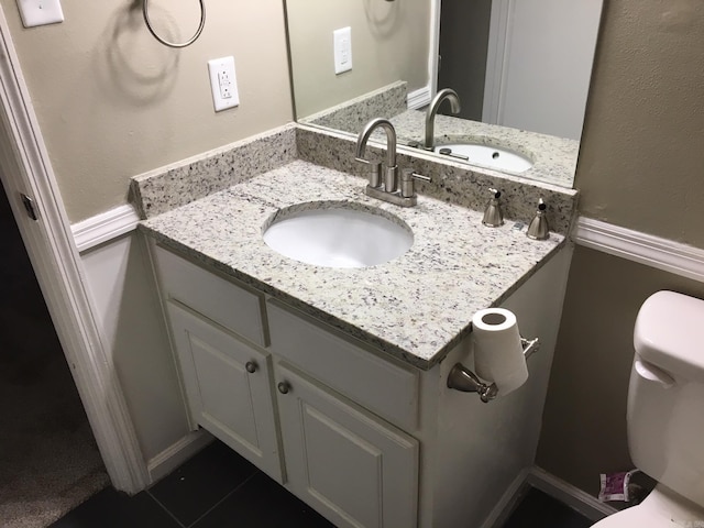 bathroom with toilet, vanity, and tile patterned floors