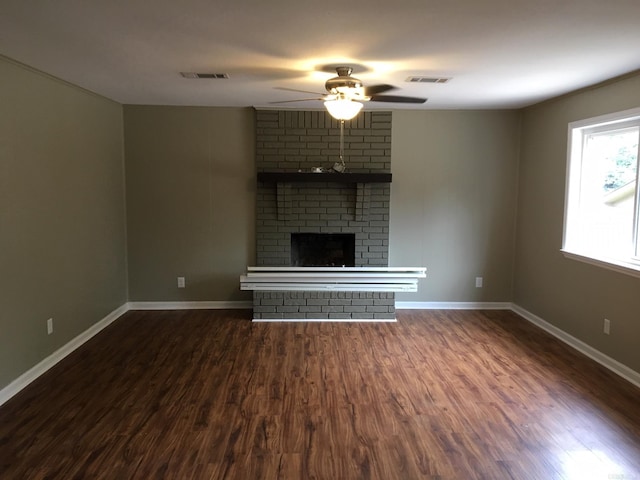 unfurnished living room featuring ceiling fan, dark wood-type flooring, and a brick fireplace