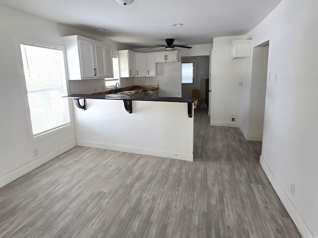 kitchen with a kitchen bar, sink, white cabinetry, and kitchen peninsula