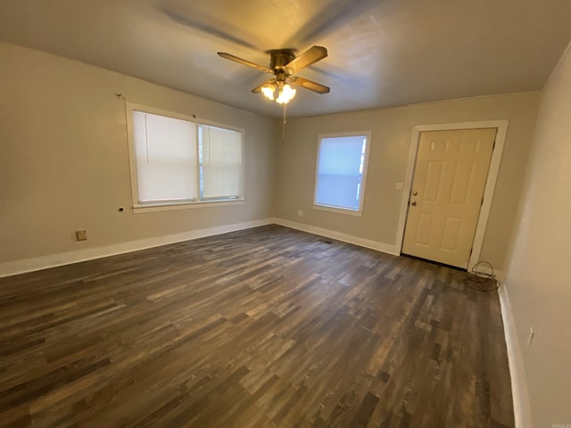 unfurnished room featuring dark wood-style flooring, ceiling fan, and baseboards