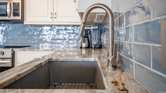 kitchen featuring backsplash, stainless steel appliances, and white cabinets