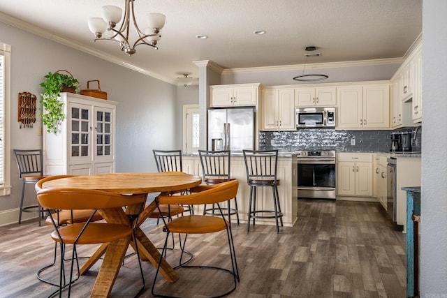 kitchen featuring dark hardwood / wood-style floors, decorative light fixtures, decorative backsplash, crown molding, and appliances with stainless steel finishes