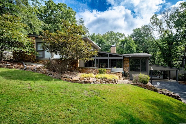 exterior space with a front yard, a carport, and a sunroom