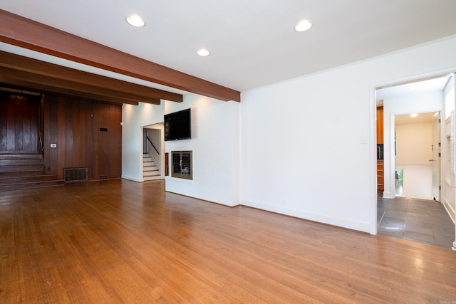 unfurnished living room with hardwood / wood-style floors and beam ceiling