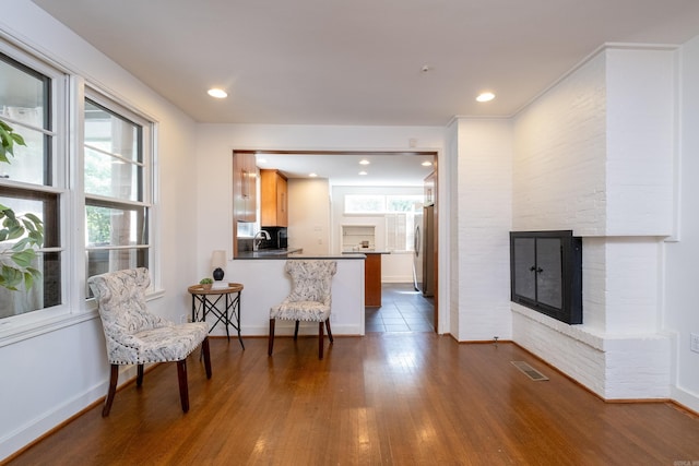 kitchen with kitchen peninsula, a healthy amount of sunlight, a breakfast bar area, a fireplace, and sink