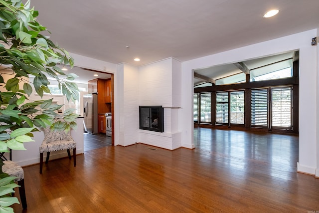 unfurnished living room featuring dark hardwood / wood-style flooring, vaulted ceiling, and a fireplace