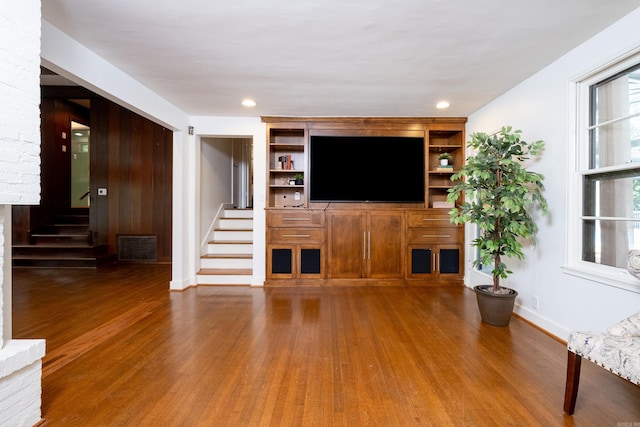 unfurnished living room with built in shelves and hardwood / wood-style flooring