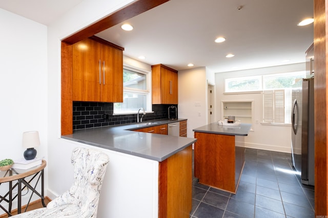 kitchen with kitchen peninsula, a center island, stainless steel appliances, backsplash, and sink