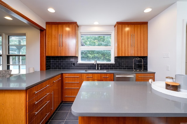 kitchen featuring sink, dark tile patterned floors, stainless steel dishwasher, and a healthy amount of sunlight