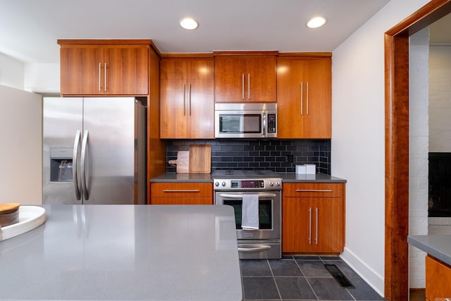 kitchen featuring dark tile patterned floors, tasteful backsplash, and appliances with stainless steel finishes