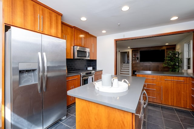 kitchen featuring stainless steel appliances, dark tile patterned floors, backsplash, and a center island