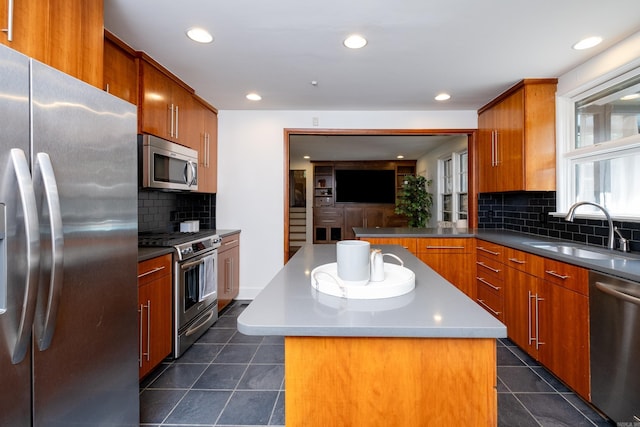 kitchen with sink, appliances with stainless steel finishes, tasteful backsplash, and a center island