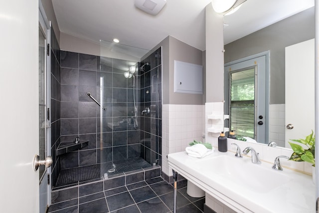 bathroom featuring tile walls, a shower with door, tile patterned floors, and sink