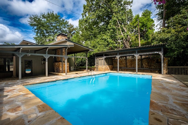 view of swimming pool with a patio area, an outdoor structure, and a pergola