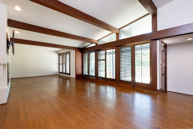 unfurnished living room featuring dark wood-type flooring and vaulted ceiling with beams