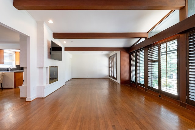 unfurnished living room with beamed ceiling and wood-type flooring