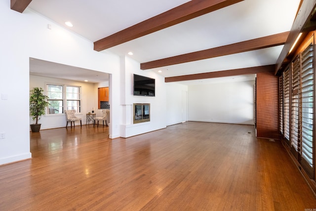 unfurnished living room with hardwood / wood-style floors and beam ceiling