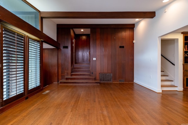 interior space featuring wood walls, hardwood / wood-style flooring, and beamed ceiling