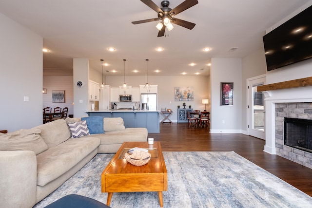 living room with a fireplace, ceiling fan, dark hardwood / wood-style flooring, and sink