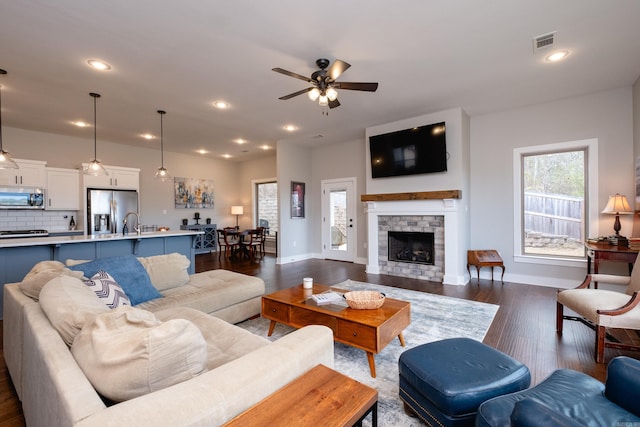 living room with ceiling fan, dark hardwood / wood-style flooring, sink, and a fireplace