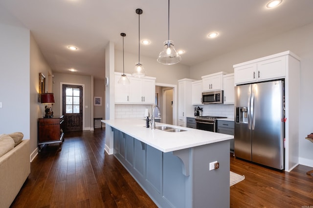 kitchen featuring decorative light fixtures, stainless steel appliances, a breakfast bar area, white cabinets, and sink