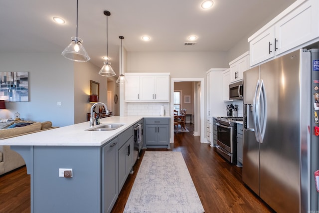 kitchen with stainless steel appliances, sink, white cabinets, decorative backsplash, and pendant lighting