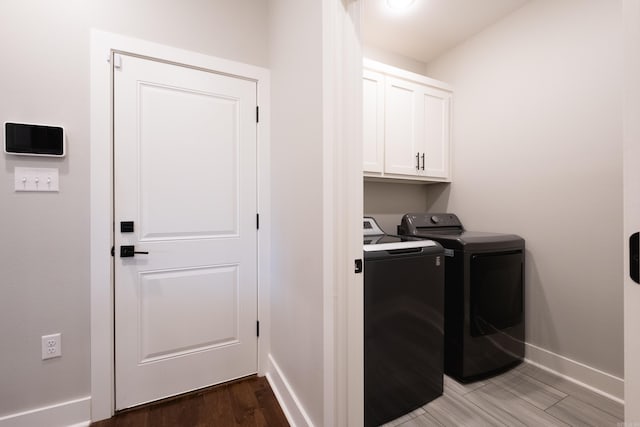 laundry area with separate washer and dryer, dark hardwood / wood-style flooring, and cabinets