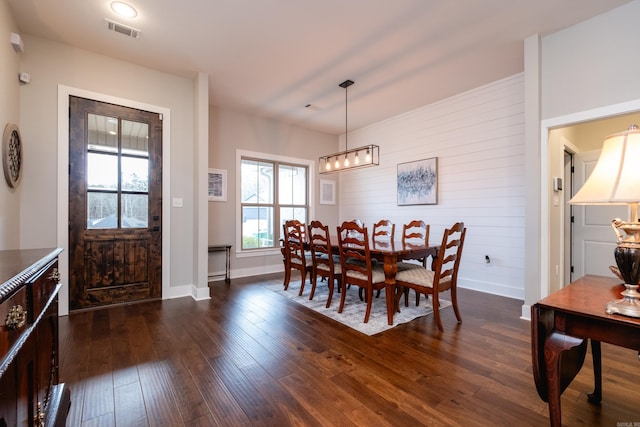 dining area with wooden walls and dark hardwood / wood-style floors