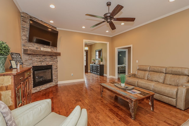 living room with a fireplace, ceiling fan, crown molding, and hardwood / wood-style flooring